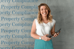 smartly dressed lady holding an ipad with the words property compliance in the background